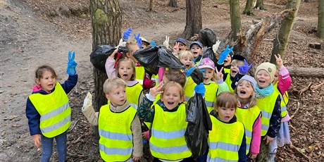 Powiększ grafikę: Grupa 4-latków pokazuje w lesie zebrane śmieci