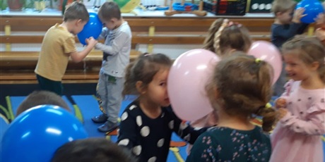 Powiększ grafikę: Smykusie tańczą w parach z balonami między głowami na sali gimnastycznej
