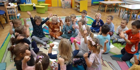 Powiększ grafikę: Dziewczynki i chłopcy z grupy Smykusiów bawią się na dywanie w sali z okazji Dnia Dziewczynek