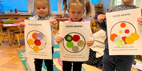 Powiększ grafikę: W sali Krasnoludków troje dzieci pokazuje swoje prace z okazji Dnia Kropki
