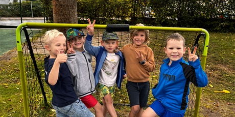 Powiększ grafikę: Pięciu chłopców pozuje do zdjęcia w bramce piłkarskiej w ogrodzie przedszkolnym