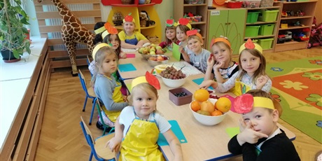 Powiększ grafikę: 10 dziewczynek 5-letnich i jeden chłopiec siedzą przy stole z owocami