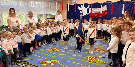 Powiększ grafikę: Dzieci i nauczycielki Doliny Smyków stoją na sali gimnastycznej z okazji Dnia Niepodległości